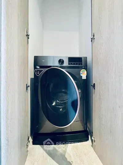 Modern washing machine in sleek storage space with wooden doors