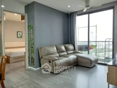Modern living room with leather sofa and city view from large window.