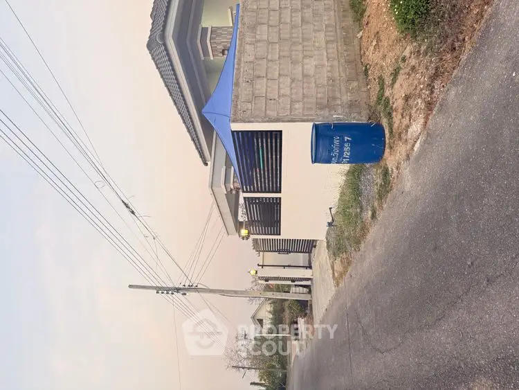 Modern residential building with sleek design and blue canopy in a serene neighborhood.