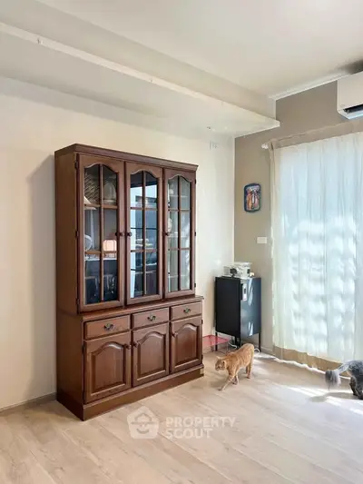 Charming living room with elegant wooden cabinet and natural light, perfect for cozy gatherings.