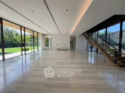 Spacious modern living room with large windows and elegant staircase