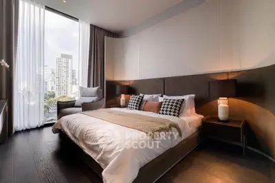 Luxurious modern bedroom with city view, featuring elegant decor and large windows.