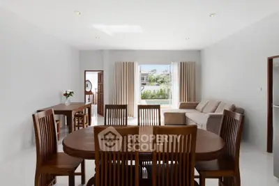 Spacious living and dining area with elegant wooden furniture and large windows offering natural light.