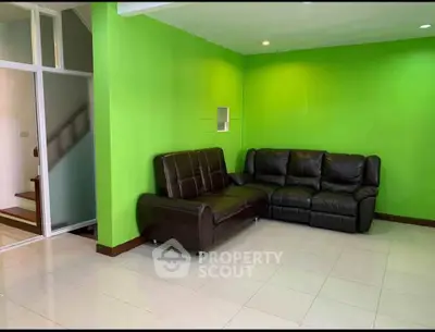 Spacious living room with vibrant green walls and leather sofas