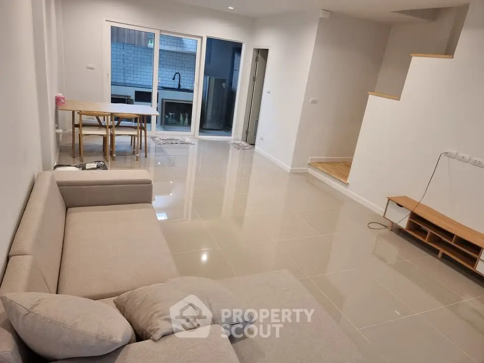 Spacious modern living room with sleek tile flooring and cozy beige sofa, perfect for relaxation and entertainment.