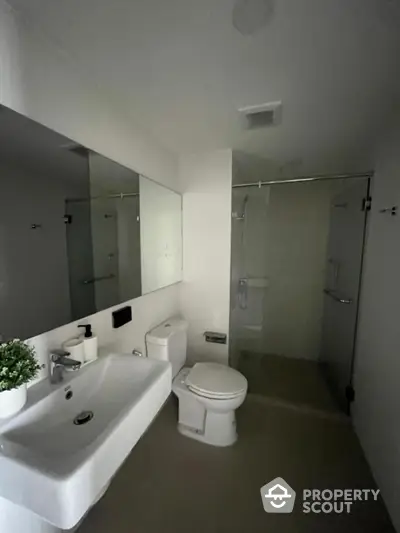 Modern bathroom with sleek design, featuring a glass shower enclosure and contemporary fixtures.