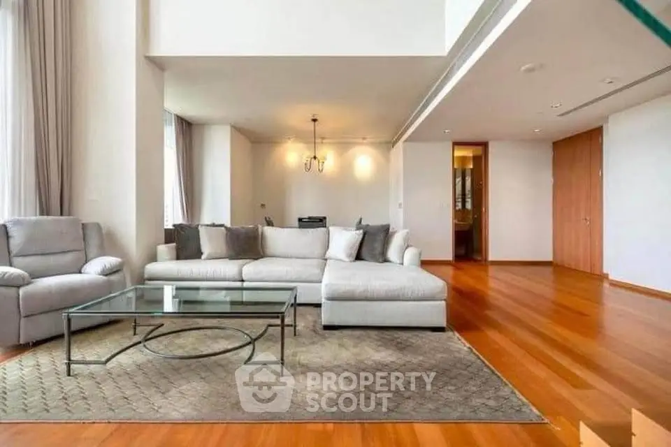 Spacious modern living room with elegant furniture and hardwood floors in luxury apartment.