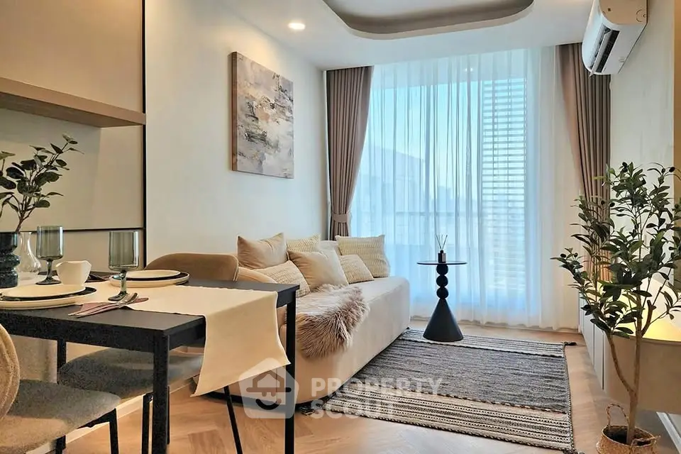 Stylish modern living room with cozy sofa, elegant decor, and large window with sheer curtains.