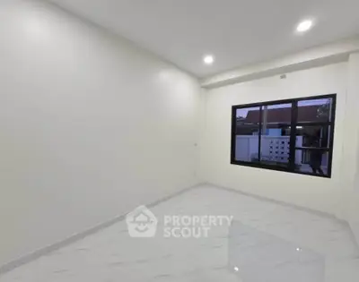 Spacious empty room with large window and modern lighting, perfect for customization.
