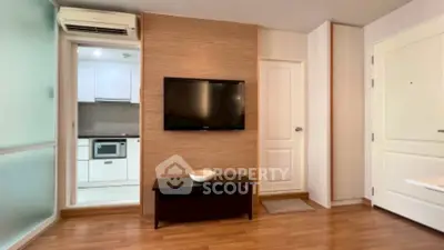 Modern living room with wall-mounted TV and view into sleek kitchen