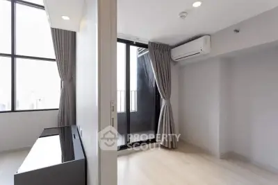 Modern minimalist living room with large windows and balcony access, featuring sleek air conditioning unit.