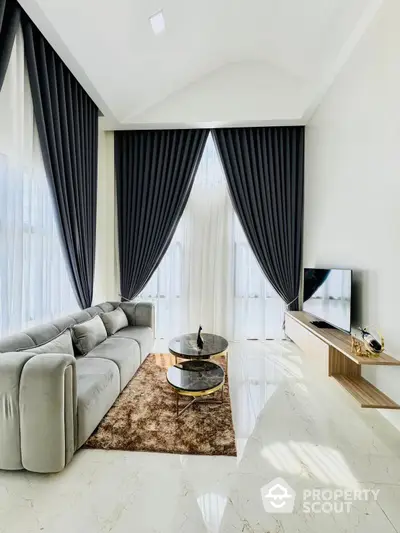 Elegant living room with polished marble flooring, luxurious grey sectional sofa, and floor-to-ceiling drapes creating a sophisticated ambiance, perfect for upscale living.