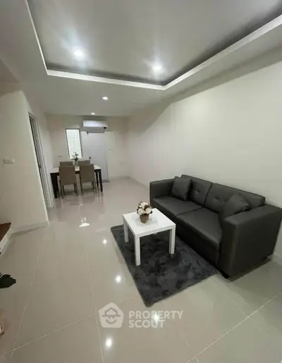 Modern living room with sleek gray sofa and elegant dining area in open layout.