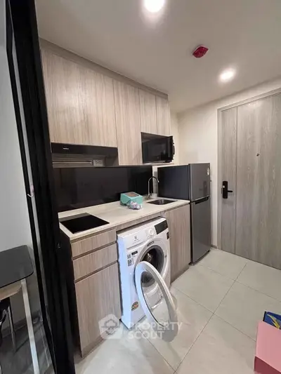 Modern compact kitchen with built-in appliances and sleek cabinetry in a stylish apartment.
