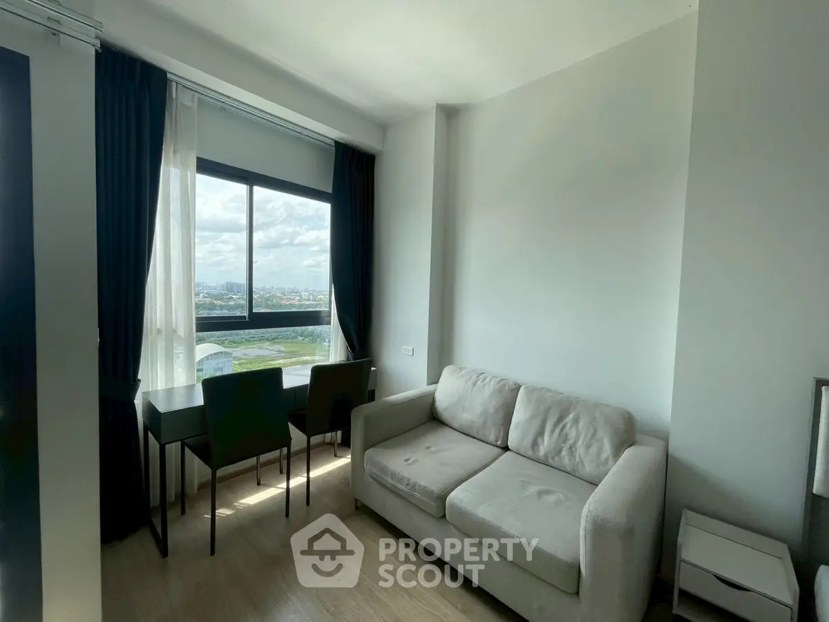 Modern living room with a cozy sofa and large window offering a stunning city view.