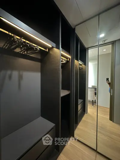 Luxurious walk-in closet with mirrored sliding doors and modern lighting