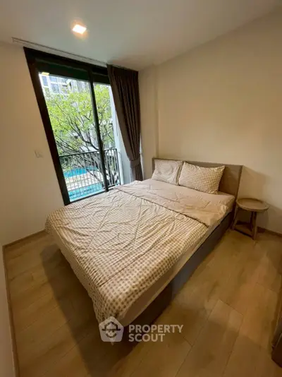 Cozy bedroom with pool view and wooden flooring, perfect for relaxation.