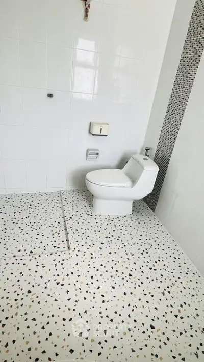 Modern bathroom with terrazzo flooring and sleek white toilet in a stylish real estate property.