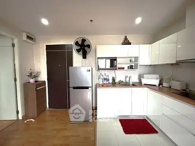 Modern kitchen with sleek white cabinets and stainless steel appliances in a cozy apartment.