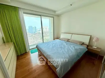 Spacious bedroom with city view and large window, featuring modern furniture and wooden flooring.