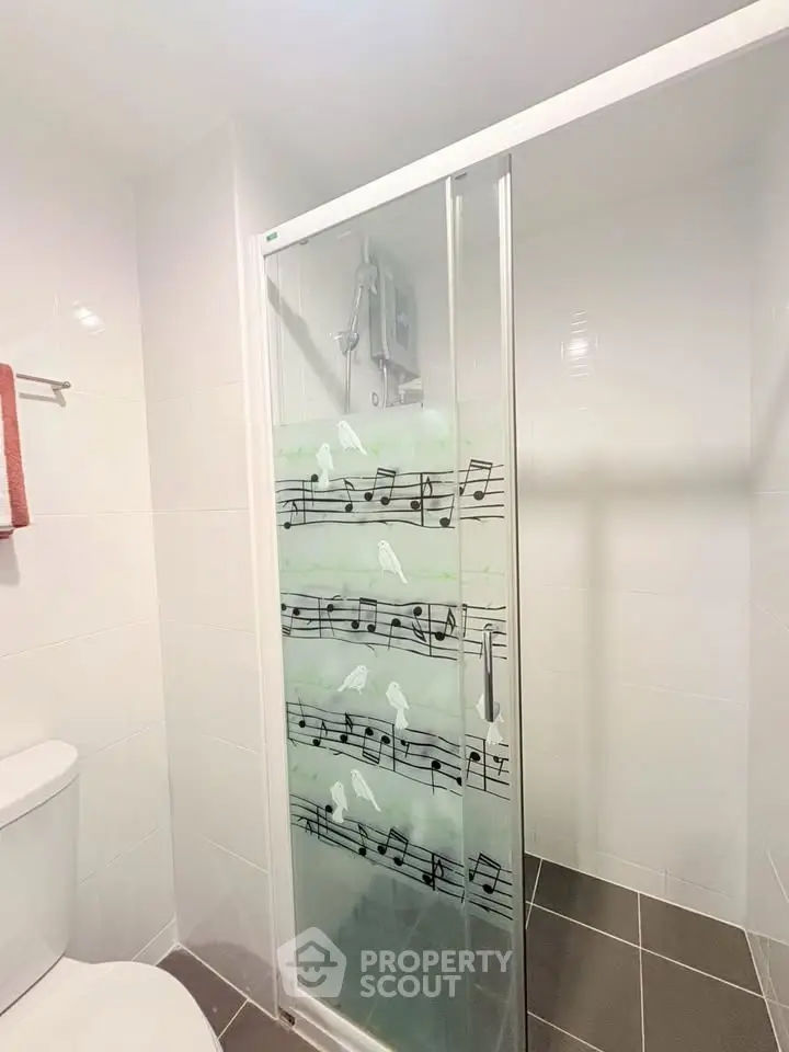 Modern bathroom with stylish glass shower door featuring musical notes design.