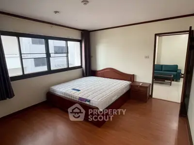 Spacious bedroom with wooden flooring and large window in modern apartment