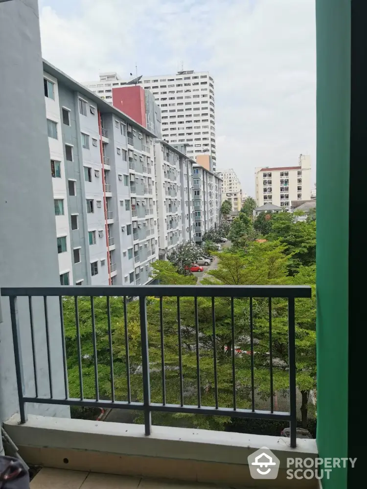 Urban apartment view from balcony overlooking cityscape and greenery.