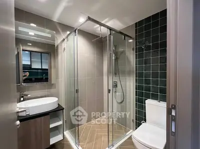 Modern bathroom with glass shower, sleek sink, and stylish tile design.