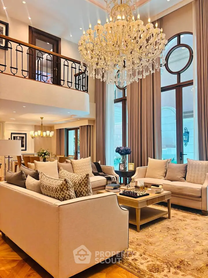 Luxurious living room with elegant chandelier and plush seating in a high-ceilinged space.