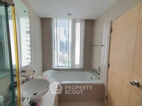 Luxurious bathroom with city view, featuring a sleek bathtub and modern fixtures.