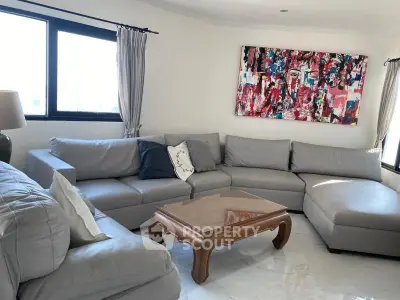 Spacious living room with modern gray sectional sofa and abstract art, perfect for relaxation and entertaining.