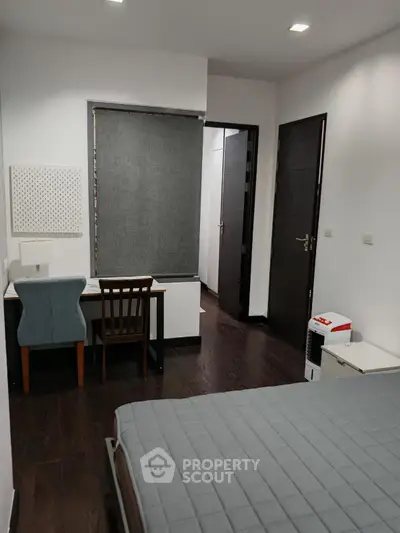 Modern bedroom with study area and dark wood flooring