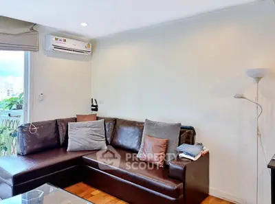 Cozy living room with leather sofa and air conditioning, perfect for relaxation.