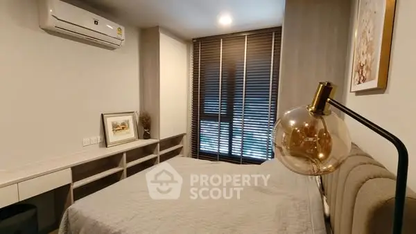 Cozy bedroom with modern decor and ample natural light from large windows.