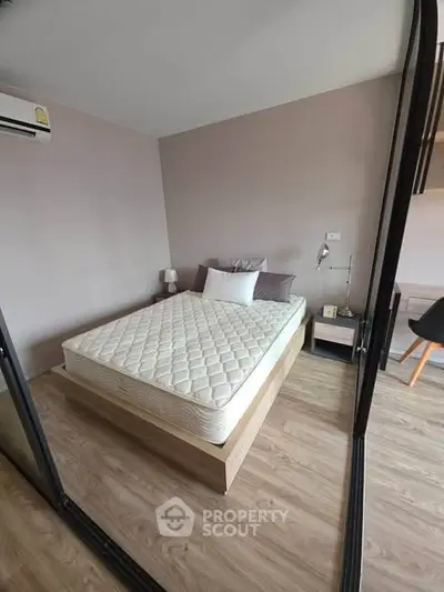 Modern bedroom with minimalist design and wooden flooring, featuring a comfortable bed and sleek furniture.