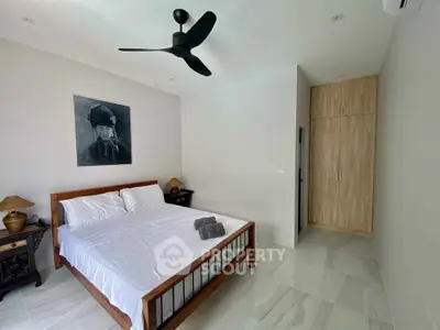 Spacious bedroom with polished marble flooring, modern wooden furniture, and a sleek ceiling fan, offering a serene and comfortable living space.