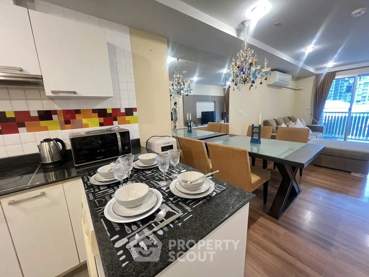 Modern open-layout kitchen and living room with elegant chandelier and stylish decor