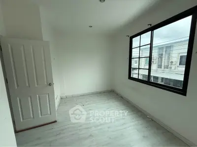 Spacious empty room with large window and white walls, perfect for customization.