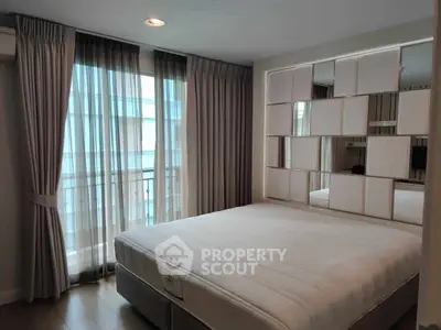 Modern bedroom with stylish mirrored wall and large window for natural light.