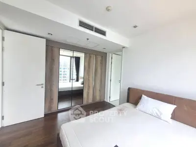 Spacious bedroom with mirrored wardrobe and modern design in a high-rise apartment.