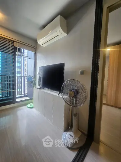 Modern living room with air conditioning and TV, featuring a sleek design and city view.
