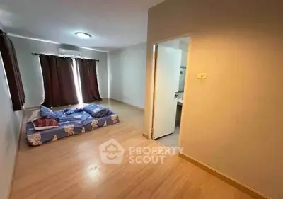 Spacious bedroom with wooden flooring and natural light, featuring a cozy bed and air conditioning.