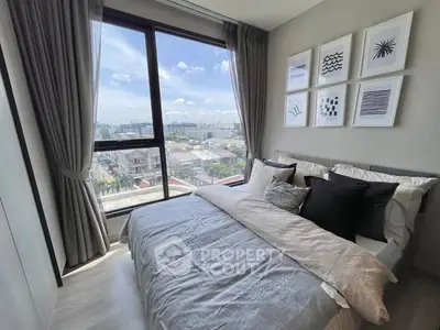 Modern bedroom with large window offering stunning city view and stylish decor.