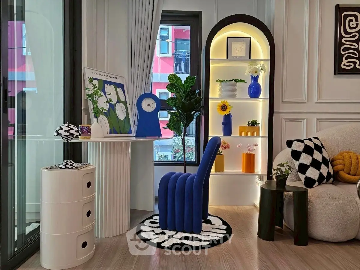 Stylish modern living room with unique blue chair, elegant decor, and bright natural light.