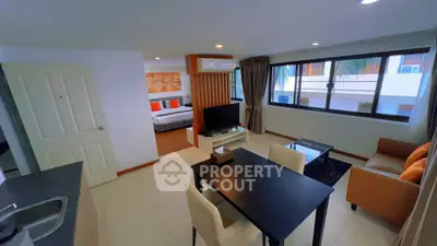 Modern open-plan living room with dining area and large windows in a stylish apartment.
