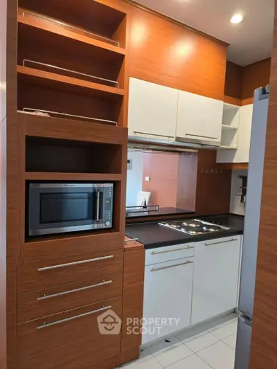 Modern kitchen with sleek cabinetry and built-in microwave in stylish apartment.