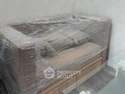 Modern living room with wrapped sofa and glass table, ready for move-in.