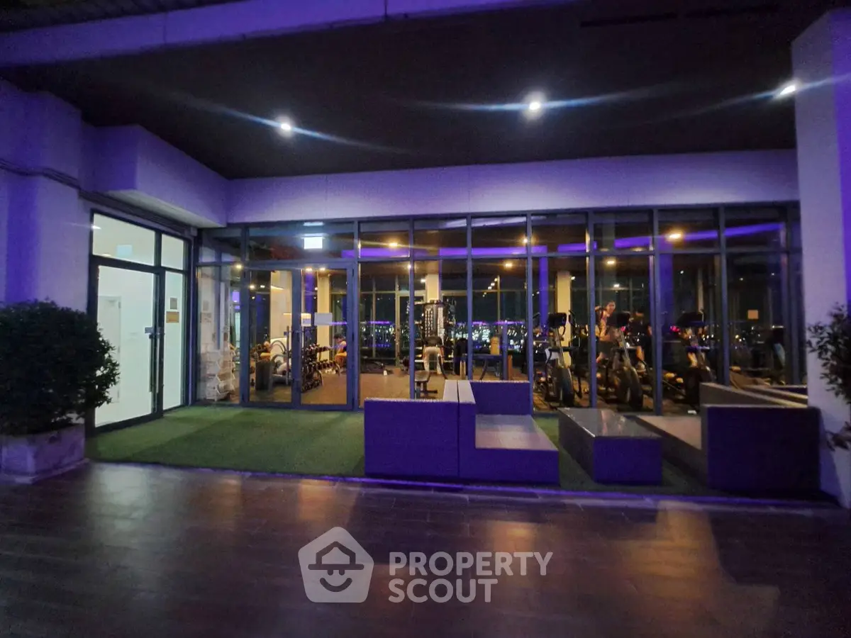 Modern gym with large windows and city view, featuring state-of-the-art fitness equipment and ambient lighting.