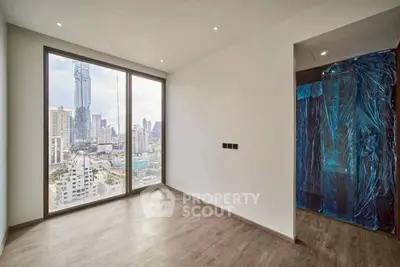 Spacious modern room with stunning city view from large windows in high-rise building.