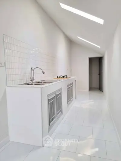 Sleek modern kitchen with white tiles and gas stove in minimalist design.